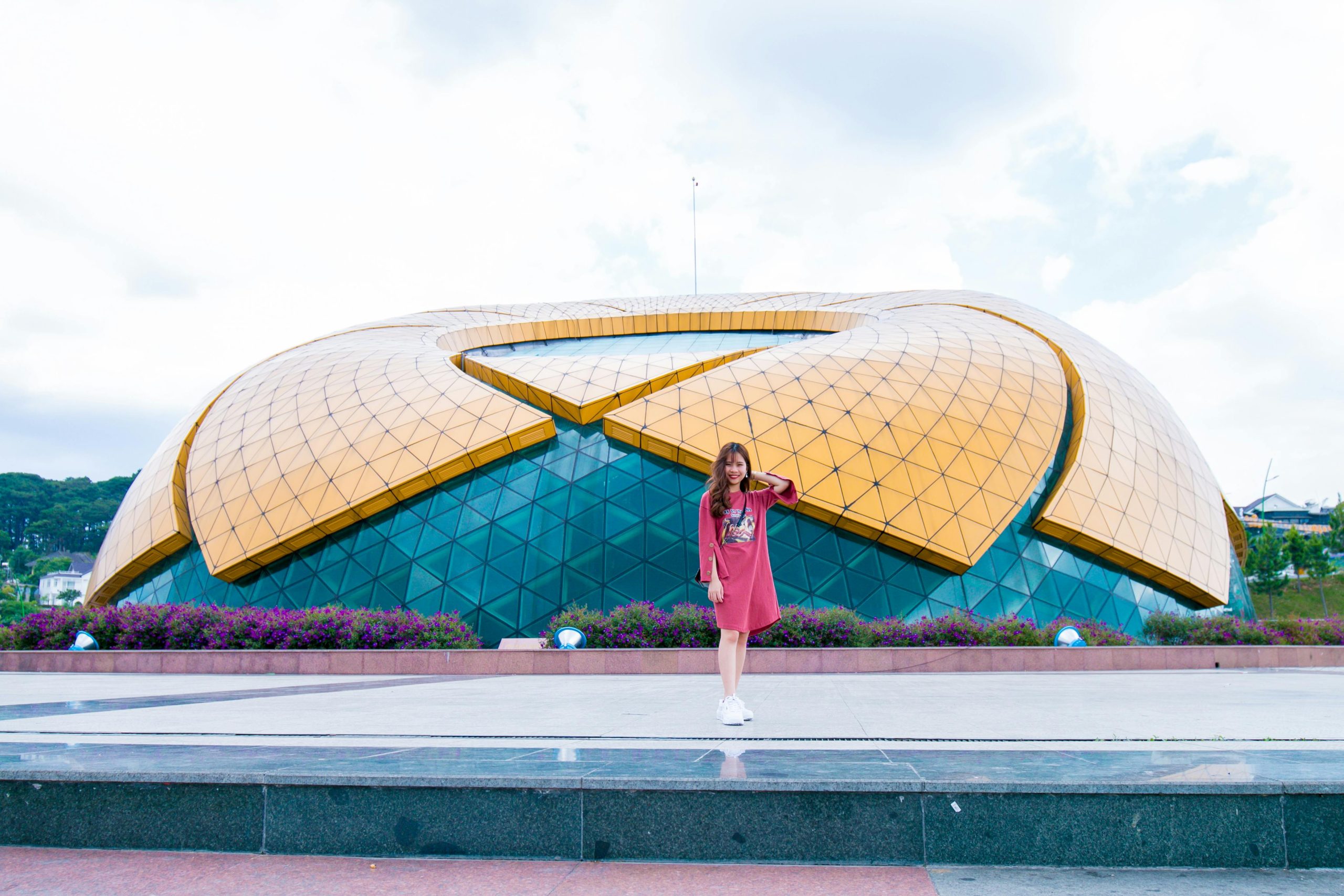 Young woman posing in front of unique modern architecture on a sunny day.