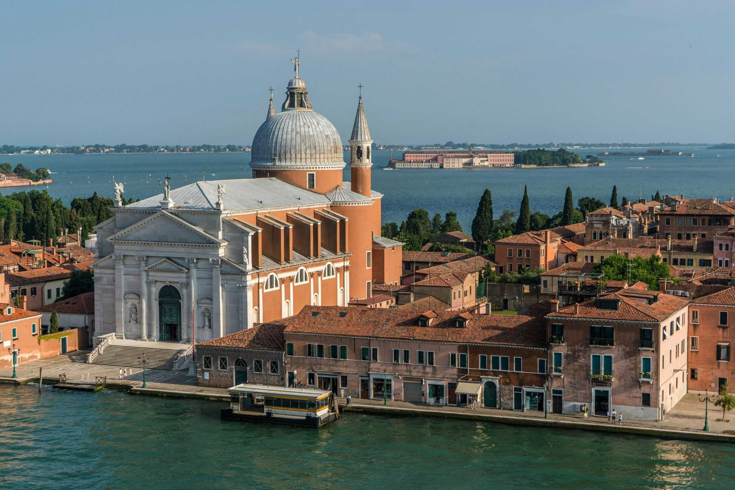 A beautiful view of a Venetian church and canal under a clear blue sky, ideal for tourism and travel themes.