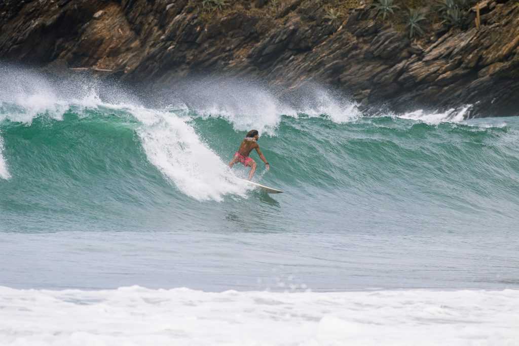 An adventurous surfer skillfully riding waves at Cuyagua Beach, Venezuela.